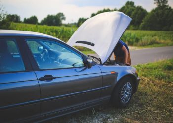 Čovek popravlja automobil na putu