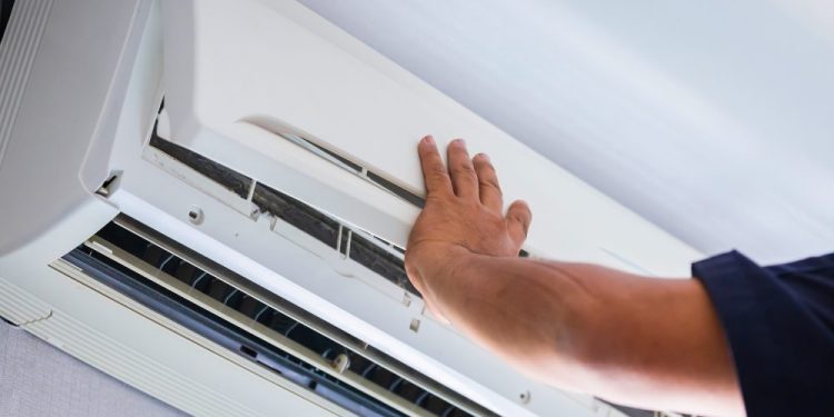 covek instalira masku na unutrasnju klimu