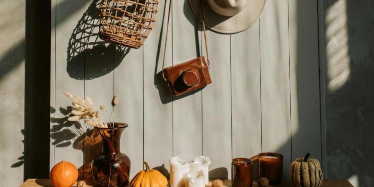 Dekoracija na komodi iznad koje su okačeni šešir, kamera i korpa