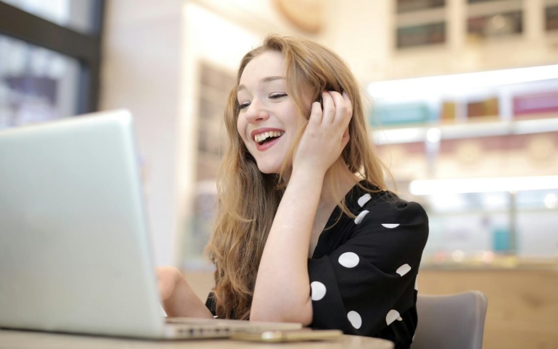 Devojka se smeje dok gleda u laptop
