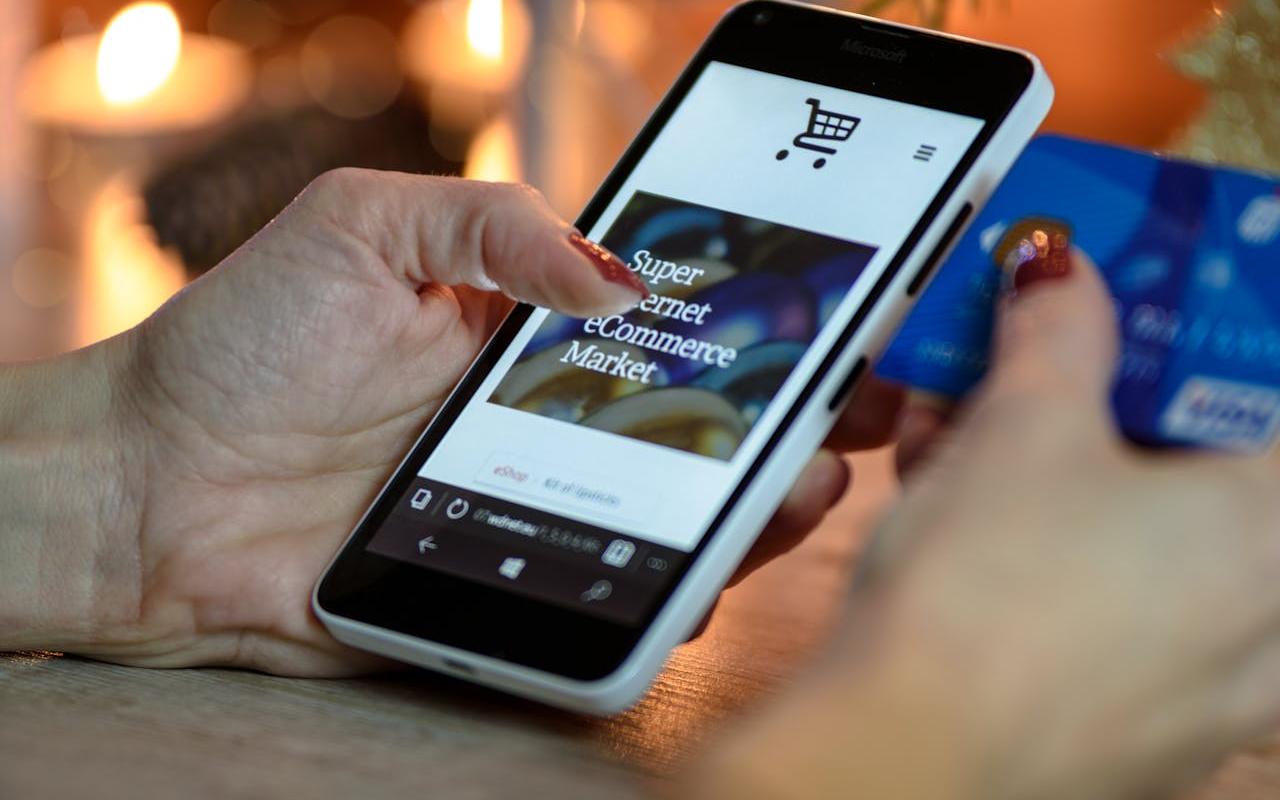 Devojka drži telefon u ruci na kojem je otvorena online prodavnica