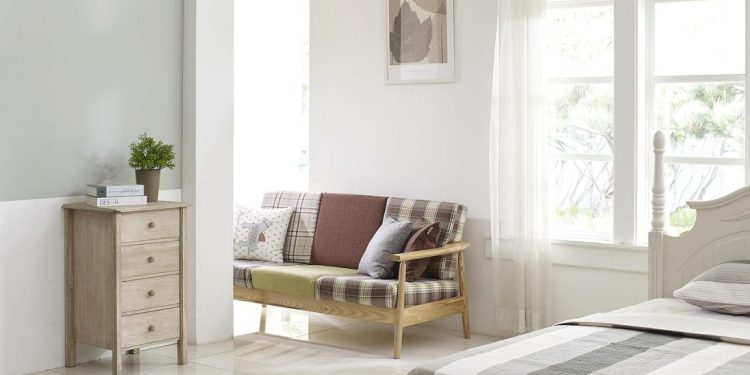 Svetao dnevni boravak sa zelenom sofom i prirodnim svetlom.