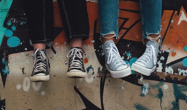 Osobe u starkama sede na betonskom zidu.