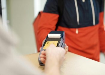 Osoba približava platnu karticu terminalu na pultu.