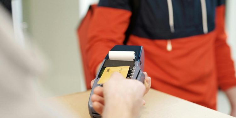 Osoba približava platnu karticu terminalu na pultu.