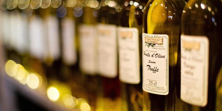 Tamne staklene boce ulja sa zlatnim čepovima.