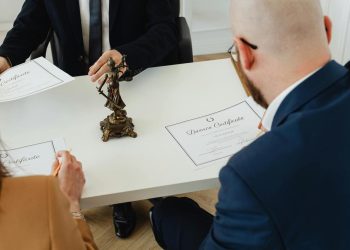 Muškarac i žena potpisuju dokumente o razvodu pored statuete Pravde