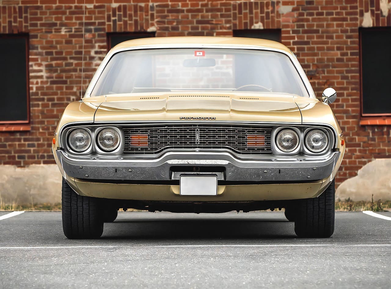 Prednji prikaz zlatnog klasičnog automobila parkiranog ispred ciglene zgrade