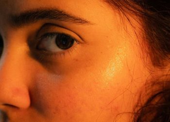 Bliži plan lica sa vidljivim okom i svetlucavim sjajem na obrazu