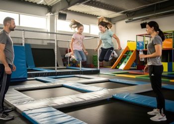 Dvoje devojčica skaču na trampolinima dok dvoje odraslih posmatraju