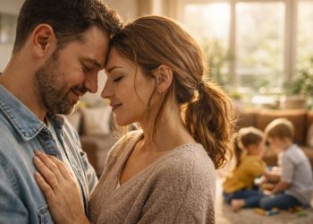 Zagrljeni bračni par, iza se deca igraju.