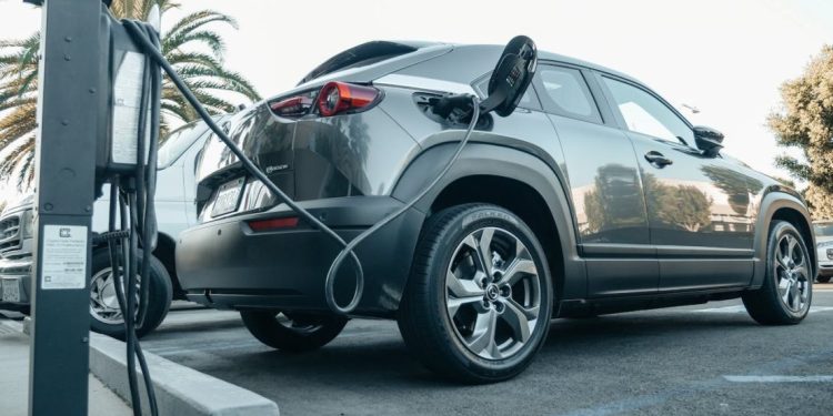 Sivi električni auto se puni na parkingu