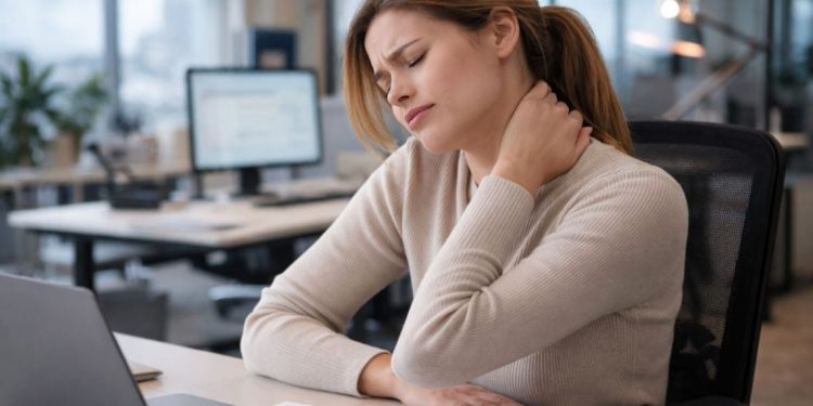 Žena sedi za kancelarijskim stolom i drži se za vrat