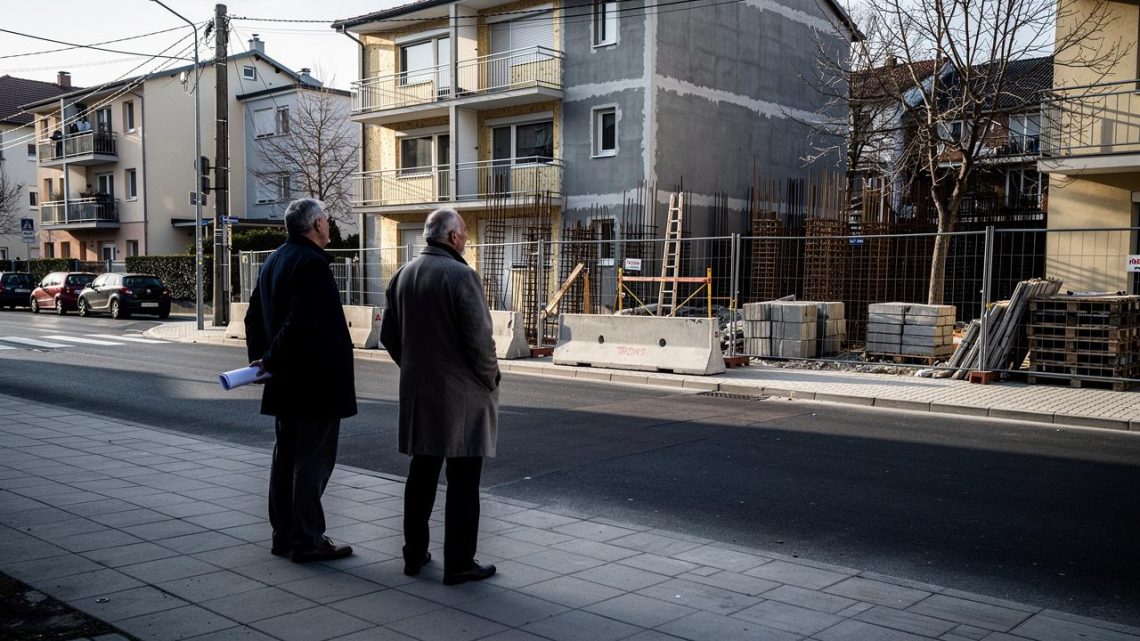 Dva muškarca stoje na trotoaru i gledaju u gradilište stambene zgrade