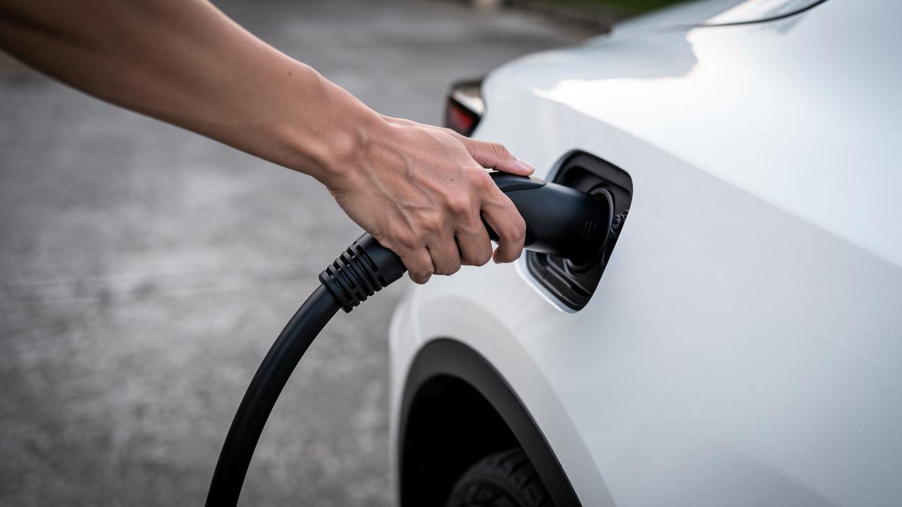 Ruka priključuje kabl za punjenje u utičnicu električnog automobila